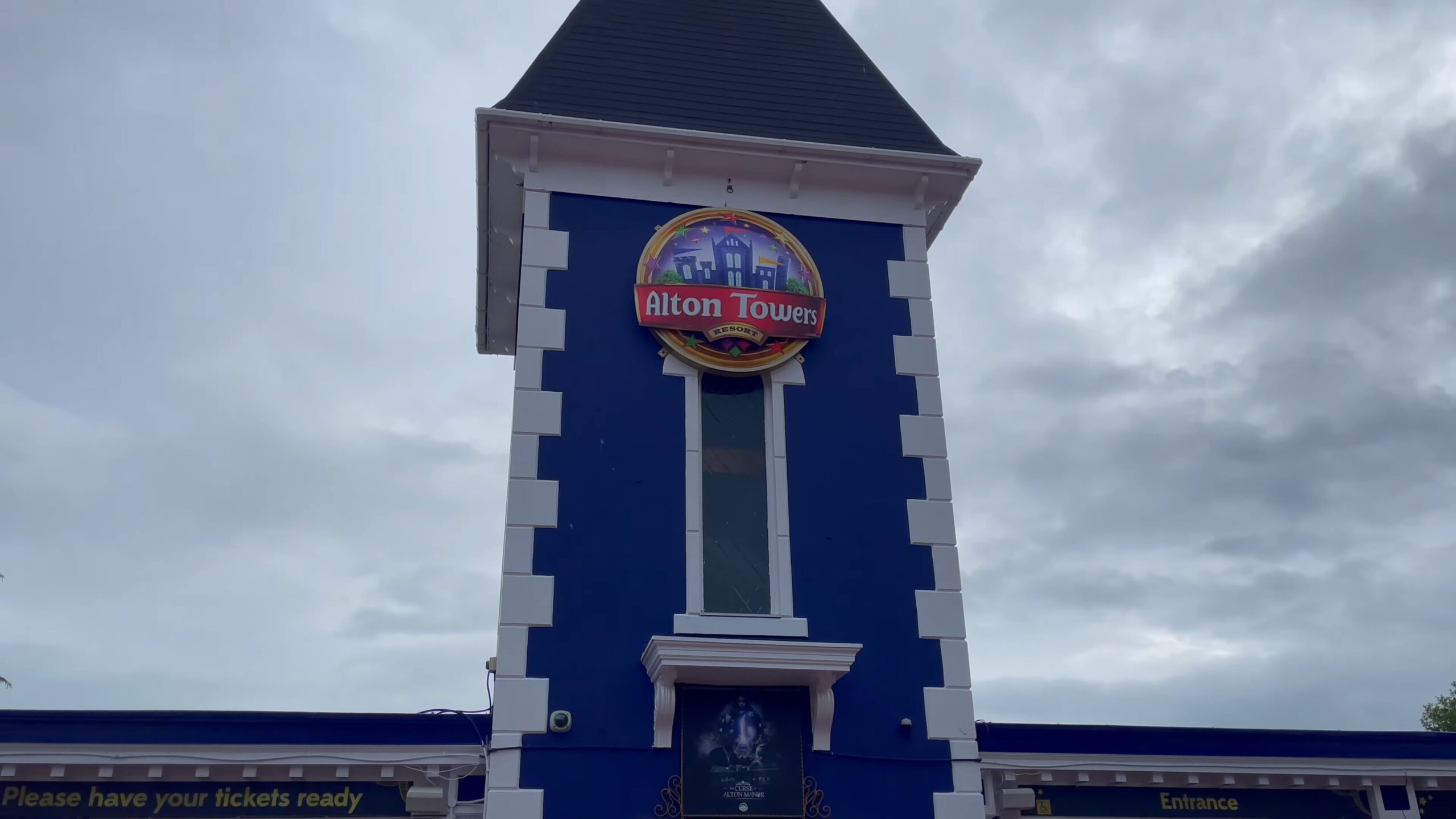 A tall blue and white entrance tower at Alton Towers Resort in the UK, featuring the park’s logo against a cloudy sky